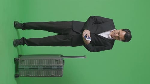 Businessman Traveler With Luggage Looking At The Passport While Standing In The Green Screen