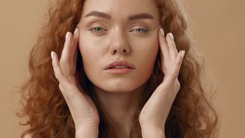 Une jeune femme aux cheveux bouclés montre des signes de stress en tenant doucement sa tête