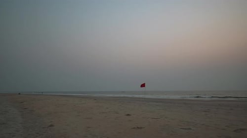 Beach Scene with Red Flag at Sunrise or Sunset