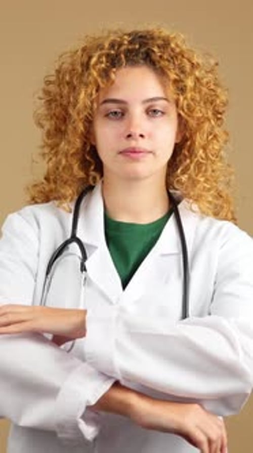 Doctora seria en bata de laboratorio con los brazos cruzados