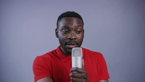 Attractive AfroAmerican Man Uses Microphone and Preaches on Grey Background Male Portrait Close Up