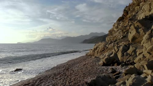 Dramatisch Meereslandschaft mit felsigem Meer und Kiesstrand, der an einem bewölkten Tag in Medi von Meereswellen bespritzt wird