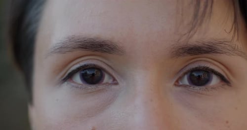 Closeup of Peaceful Female Face and Eyes with Contact Lenses Looking at Camera Outdoors