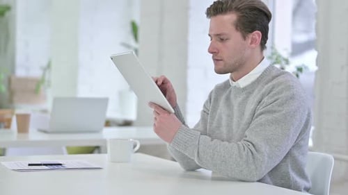 Hardworking Creative Young Man using Tablet in Office