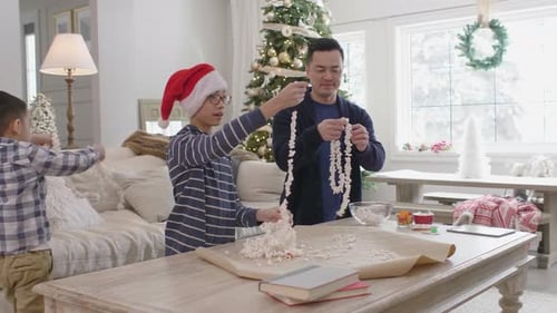 Family makes Christmas garland in bright living room