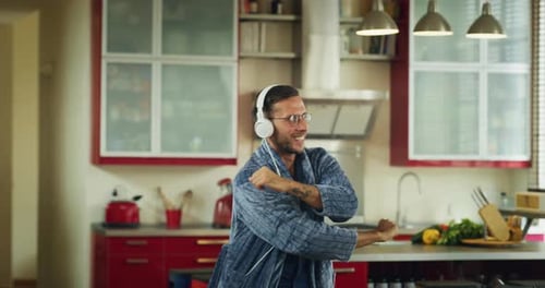 Happy Man Dancing in His Kitchen With Headphones