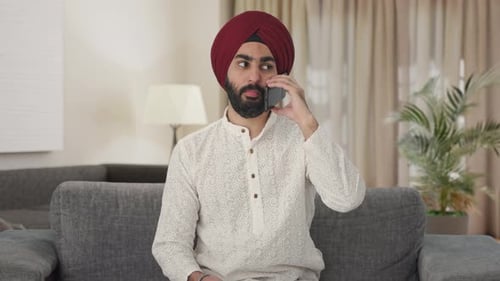 Man in Turban Talks on Phone in Living Room