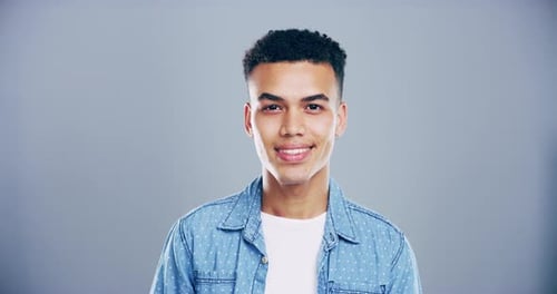 4K video footage of a young man smiling against a grey studio background