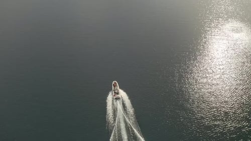 Slow motion aerial shot of a boat navigating in Lacar lake and revealing the landscape