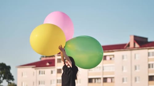 Happy Girl with Big with Colorful Balloons Posing on the Background of City Houses