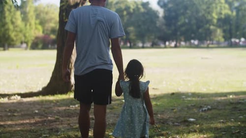 Rear View of Man Walking with Toddler Daughter in Park