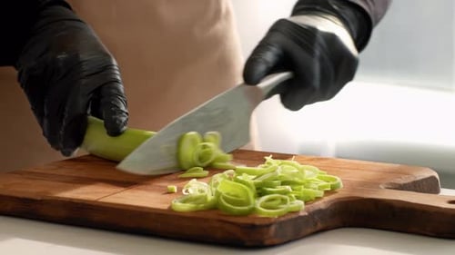 Koch bereitet frischen Lauch auf einem Holzschneidebrett in einer modernen Küche zu