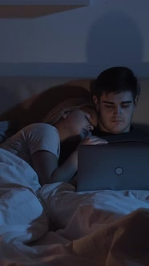 Couple in Bed with Laptop at Night