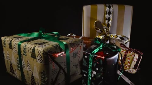 Downward Moving Over Wrapped Christmas Gifts With Ribbons On Black Background Under Studio Light