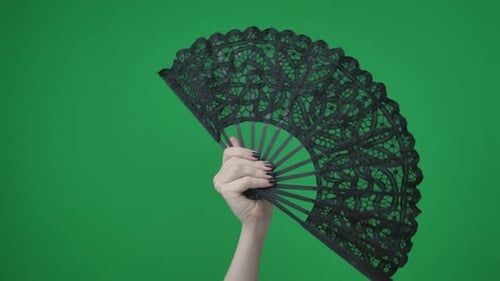 Na moldura em um fundo verde, uma chave cromada, mão feminina com manicure, segura um orifício preto