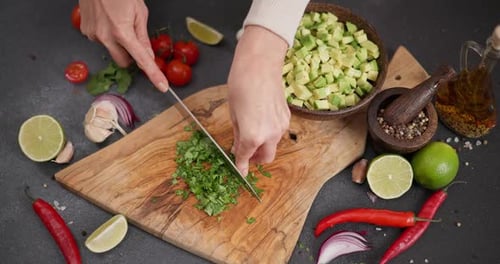 Salsa-Rezept Frau schneidet und hackt Koriander- oder Petersiliengrün auf einem Holzschneidebrett bei