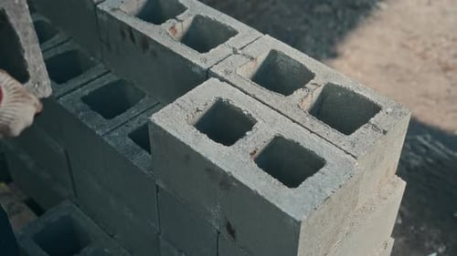 Stacking Gray Cinder Blocks with Gloved Hands