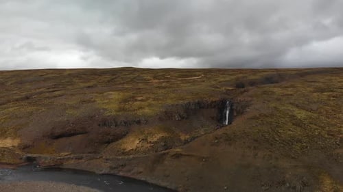 Aerial footage moving towards a waterfall located in the highlands up in the mountains of Iceland.