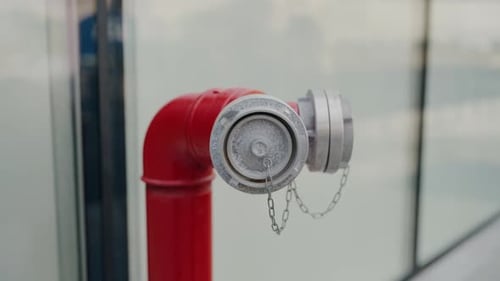 Das rote Hydrantenrohr steht auf der Straße in der Nähe der Fenster des Bürogebäudes in Nahaufnahme