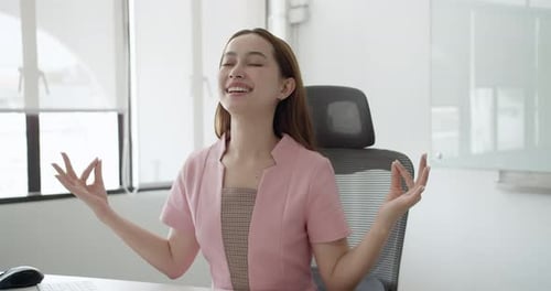 Young Woman Meditating at Desk in Office