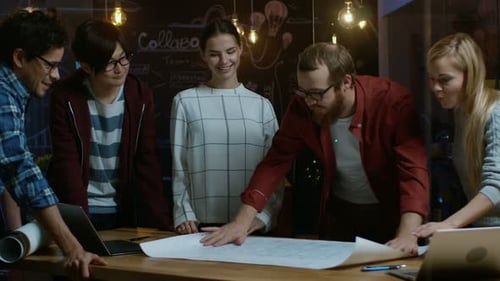 Team Discussing Blueprints at Wooden Table in Office