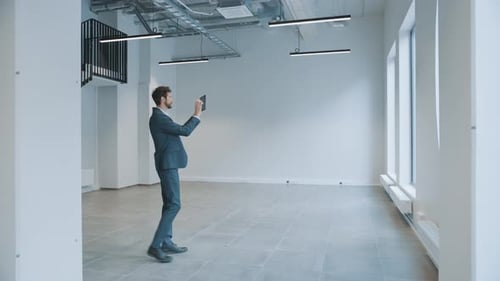 Man in Suit Inspecting Empty Office with Tablet