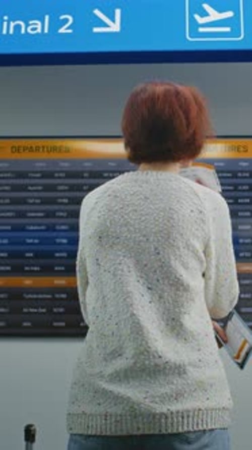 Passengers Checking Departures on Flight Information Screen In International Airport Terminal