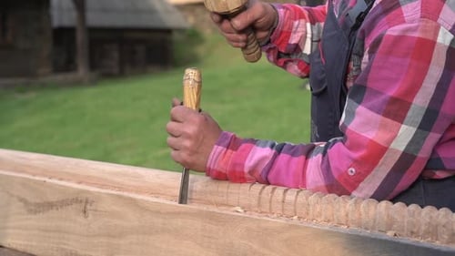 Un charpentier sculpte avec un ciseau