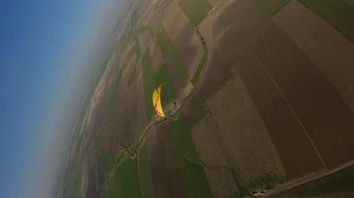 Vertikales Format: Luftabstiege vorbei am gelben Baldachin des Gleitschirms