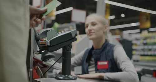 Woman Processing Payment at Supermarket Checkout Counter