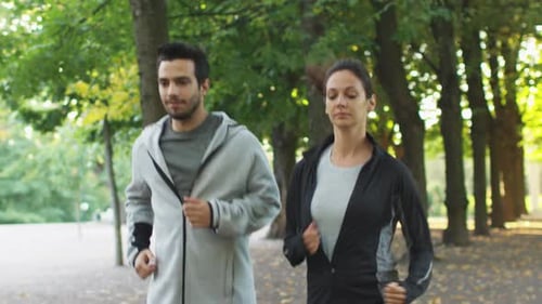 Attractive Woman and Man Running Forward in Park at Bright Summer Day