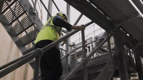 Man Climbing Metal Industrial Stairs in Safety Gear