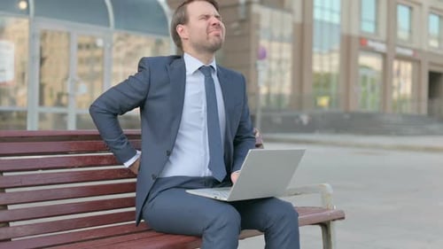 Man in Suit Using Laptop Experiences Back Pain