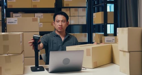 Young Adult Working in Warehouse Scanning Packages