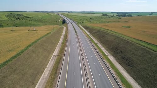 Aerial View of a Cars Driving Through Highway Road Among Agriculture Fields and Green Countryside