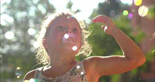 Authentic shot of two cute little girls having fun playing with soap bubbles outside their house o