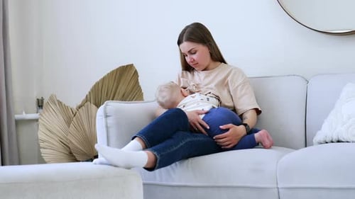 Mother Breastfeeding Infant on Comfortable Couch Indoors