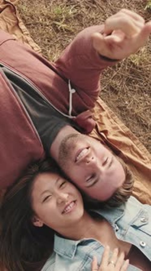 Young couple lying on blanket in the park from outside