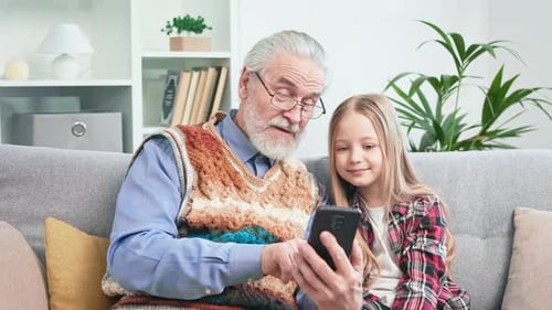 Grandfather and Grandchild Use Smartphone on Couch