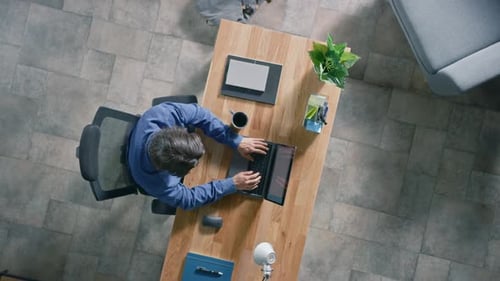 Businessman Sitting at His Desk in the Office Uses Laptop Computer,