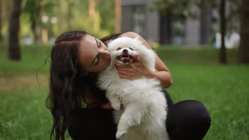 Joyful Moments A Woman and Her Adorable White Pomeranian Enjoying Time in the Park
