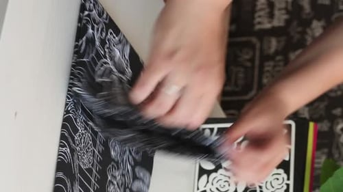 Hands Unwrapping a Fabric Gift on White Table