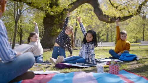 Teacher and children enjoying sunny group education in city park