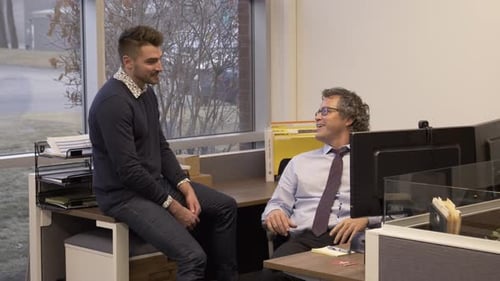 Dos hombres hablando en la oficina y mirando la computadora