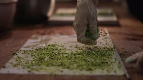 Pastry chef with gloved hand sprinkles the dessert dough with seeds