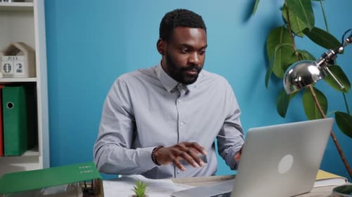 A Focused Professional Engaged in Their Work at a Desk with a Laptop in an Office Setting