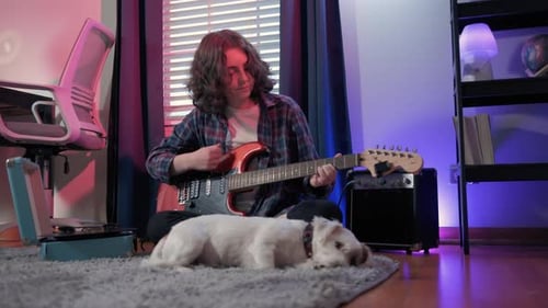 Young Adult Playing Guitar with Dog in Room