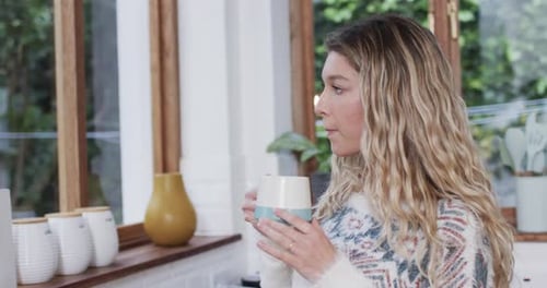 Blonde Woman Smiling and Drinking in Kitchen