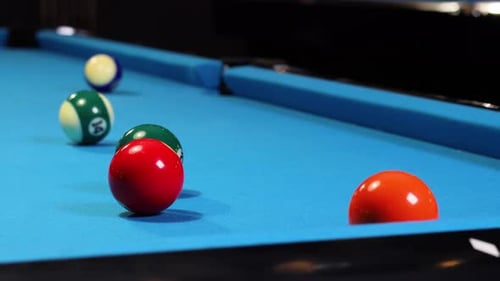 Playing a game of billiards pool hitting green ball with cue ball.