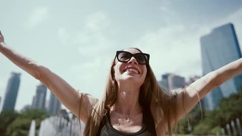 Mujer feliz jugando con su larga cabellera rubia en Urban View en verano, retrata emociones positivas y